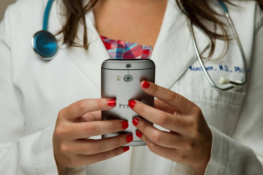 Doctor in a white coat with a stethoscope using a smartphone